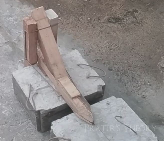 Two concrete blocks and a wooden divice sat on top of one of the blocks